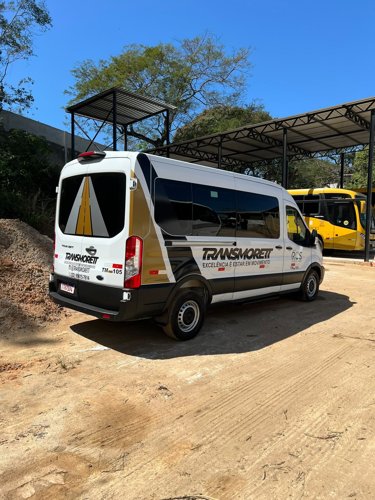 Van executiva Transmorett estacionada em pátio, vista traseira, ao lado de outros veículos da frota